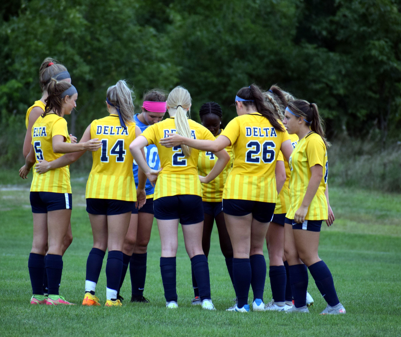 Girls soccer team in a huddle during a game.