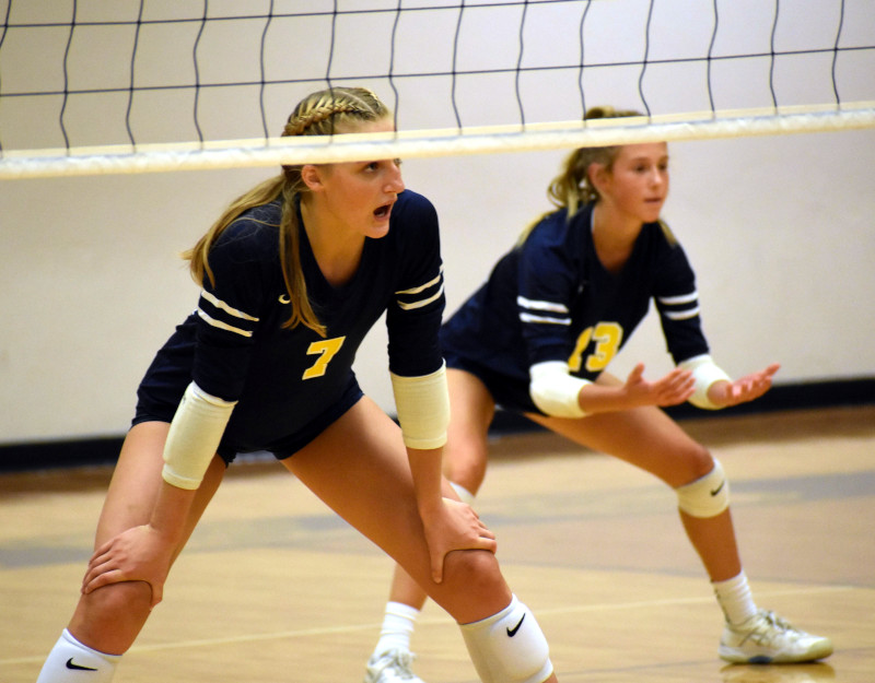 two volleyball players prepare for a serve.